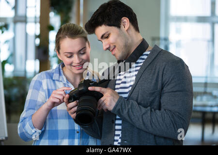 Felice fotografo mostra un'immagine a un collega in ufficio creativo Foto Stock