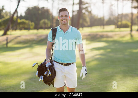 Ritratto di giovane sorridente uomo che porta borsa da golf Foto Stock