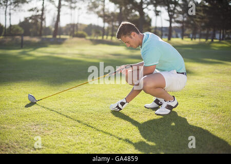 Vista laterale del giovane posizionando la pallina da golf sul raccordo a T Foto Stock