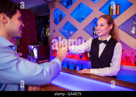 Barista sorridente mentre serve da bere al cliente maschio Foto Stock