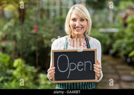 Donna matura tenendo aperte targhetta di segno Foto Stock