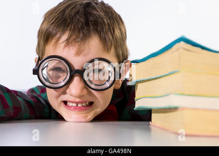 Giocoso ragazzo appoggiata sul tavolo in aula Foto Stock