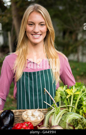 Ritratto di felice giardiniere con verdure fresche in cesto in giardino Foto Stock