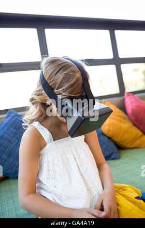 Ragazza con la realtà virtuale cuffie mentre è seduto in biblioteca Foto Stock