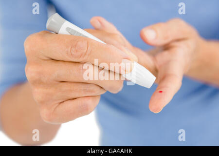 Donna che utilizza il livello di glucosio nel sangue monitor Foto Stock