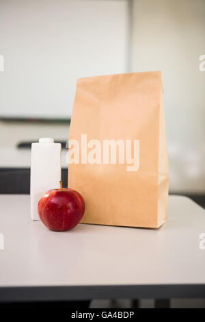 Apple con bottiglia di bevanda e sacchetto di carta sul tavolo in aula Foto Stock