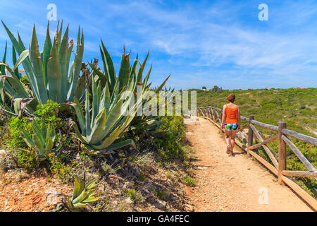 Giovane donna tourist camminando sulla via costiera lungo la baia mare, Portogallo Foto Stock