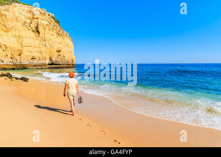 Giovane donna tourist camminando lungo la spiaggia di sabbia dorata spiaggia Centianes, Portogallo Foto Stock