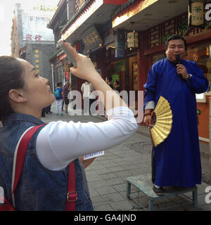 Donna di fotografare e un commesso al di fuori del negozio, Dashilar Hutong distretto, a Pechino, in Cina. Foto Stock