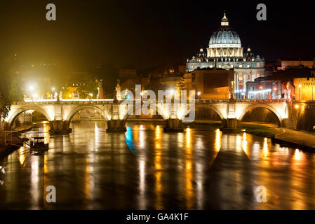 Vista notturna sul Sant Angelo Bridge e la Basilica di San Pietro in Roma, Italia Foto Stock