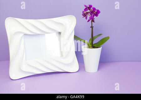 White photo frame e poco orchid in viola. Foto Stock