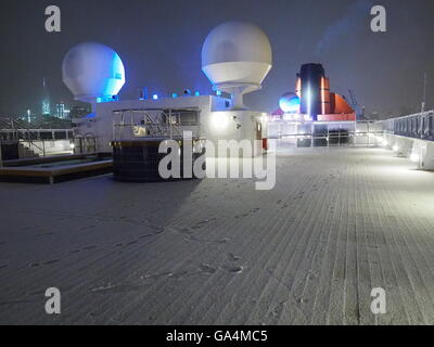 Inserito in New York su una metà Gennaio sera, lo skyline di New York è visto da una coperta di neve il ponte 13 della Queen Mary 2. Foto Stock