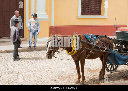 Carrozza trainata da cavalli e tre uomini di parlare al di fuori del Museo Nazionale de la lucha contra Bandidos, Trinidad, Cuba Foto Stock