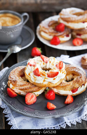 Soffio di crema anelli (bignè) decorate con fragole fresche e salsa di caramello Foto Stock