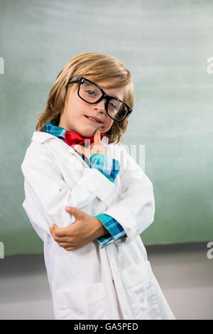 Ragazzo vestito come scienziato in piedi in aula Foto Stock