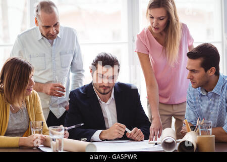 Imprenditore con i colleghi di lavoro guardando il blueprint Foto Stock