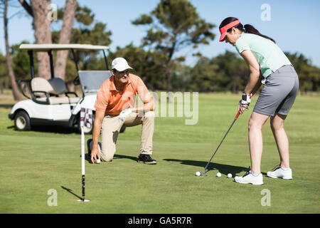 Donna giocando a golf mentre in piedi da uomo Foto Stock