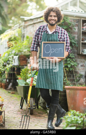 Giardiniere maschio con segno aperto mantenendo la forcella di giardinaggio Foto Stock