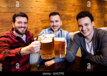 Ritratto di amici maschi la tostatura la birra al ristorante Foto Stock