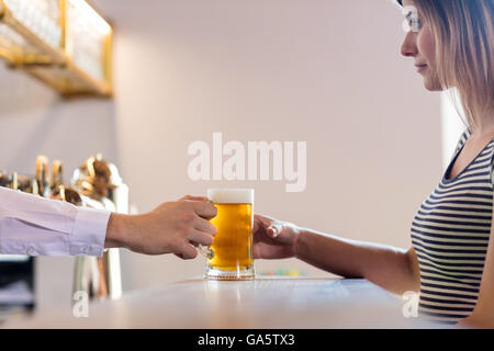 Il barista che serve birra per clienti di sesso femminile Foto Stock