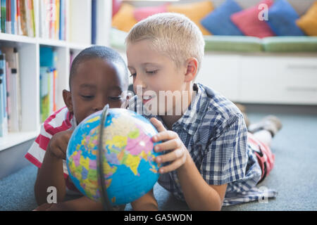 La scuola i ragazzi studiano globo in biblioteca Foto Stock