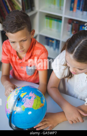 La scuola i ragazzi studiano globo in biblioteca Foto Stock