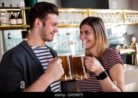Felice coppia giovane tostare il boccale di birra Foto Stock