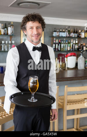 Cameriere tenendo un vassoio con un bicchiere di birra Foto Stock