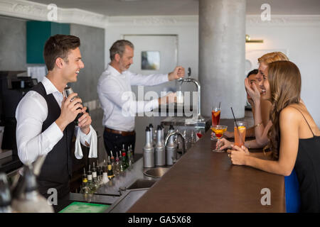 Bella donna avente un cocktail mentre cameriere preparare cocktail con shaker Foto Stock