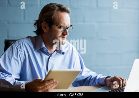 Focalizzato l'uomo utilizzando computer portatile in ufficio Foto Stock