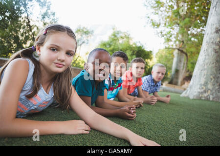 Sorridente schoolkids giacente su erba nel campus Foto Stock