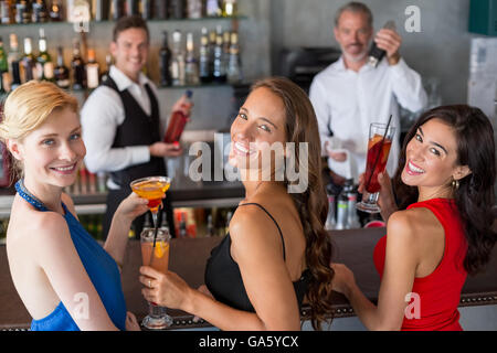 Happy amici di sesso femminile tenendo un bicchiere di cocktail al bancone bar Foto Stock