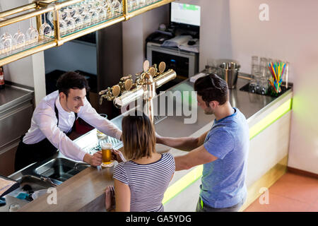 Barman che serve birra per paio Foto Stock