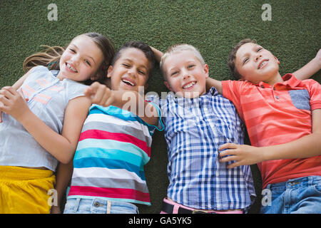 Sorridente schoolkids giacente su erba nel campus Foto Stock