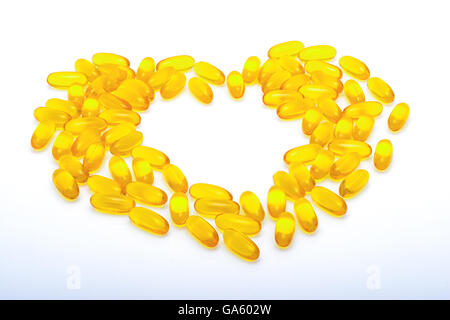 Olio di pesce capsule, vitamine giallo, a forma di cuore su sfondo bianco Foto Stock