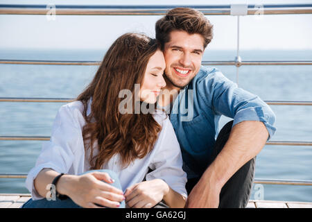 Ritratto di un uomo sorridente e una donna seduta insieme al mare Foto Stock