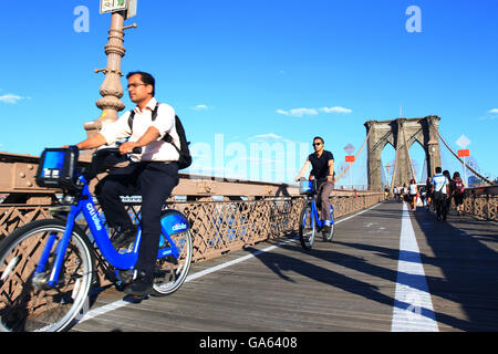 I turisti in viaggio attraverso il Ponte di Brooklyn a New York su Citibike biciclette a noleggio durante l'estate. Foto Stock