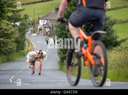 I concorrenti prende parte sulla paglia Oxenhope gara nello Yorkshire, che comporta l'esecuzione in costume durante l'esercizio di una balla di paglia e la visita a ciascuno dei pub locale nel villaggio per raccogliere fondi per le associazioni di beneficenza locali. Foto Stock