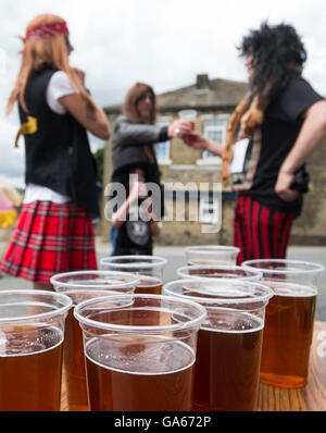 I concorrenti prende parte sulla paglia Oxenhope gara nello Yorkshire, che comporta l'esecuzione in costume durante l'esercizio di una balla di paglia e la visita a ciascuno dei pub locale nel villaggio per raccogliere fondi per le associazioni di beneficenza locali. Foto Stock