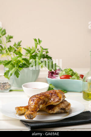 Arrosto di cosce di pollo con lattuga e pomodoro su bianco tavolo in legno Foto Stock