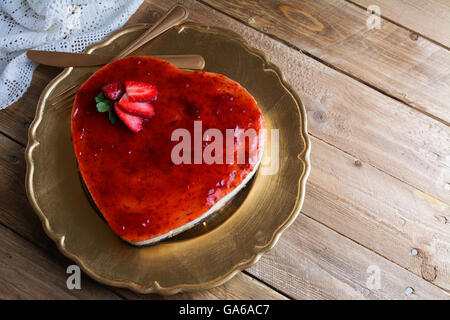 A forma di cuore ad cheesecake con gelatina di lamponi su una piastra di oro decorate con fragole Foto Stock