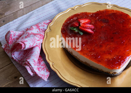 A forma di cuore ad cheesecake con gelatina di lamponi su una piastra di oro decorate con fragole Foto Stock