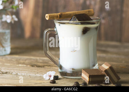 La tazza di ghiaccio il caffè con il latte, con cioccolatini sul rustico texture di legno Foto Stock