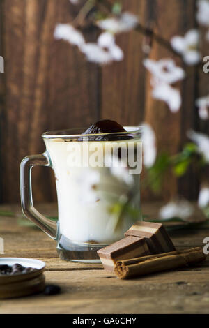 La tazza di ghiaccio il caffè con il latte, con cioccolatini sul rustico texture di legno Foto Stock