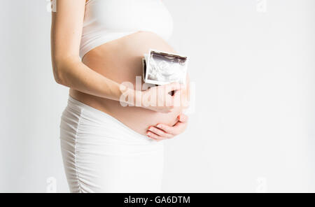 Una donna incinta detiene un ultrasuono di fronte la sua gravidanza pancia. Foto Stock