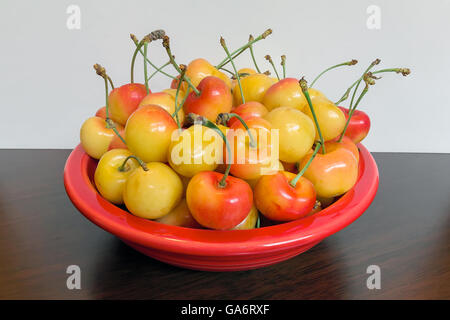 Pila di ciliegie Rainier in una vaschetta di colore rosso e su un tavolo di legno macro Foto Stock