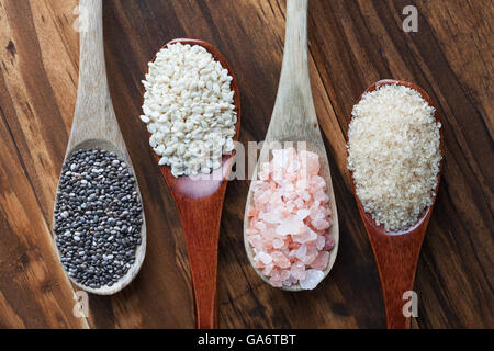 Rosa himalayano sale, zucchero greggio di canna, di sesamo nero e semi di Chia in cucchiai di legno, vista dall'alto Foto Stock