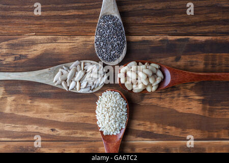 Il girasole, nero Chia, i semi di sesamo e pinoli in cucchiai di legno. Vista da sopra con copia spazio. Foto Stock