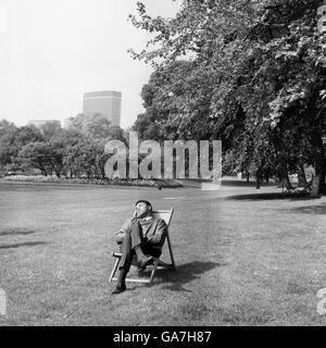 Campione del mondo di pesi massimi Muhammad Ali si rilassa in un parco vicino al suo hotel. La notte prima di battere lo sfidante britannico Henry Cooper dopo un taglio negativo all'occhio di Henry Cooper ha fermato la battaglia nel sesto round dell'Arsenal's Highbury Stadium. Foto Stock