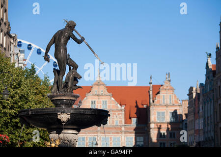 Una statua del dio del mare Nettuno montato sulla famosa fontana nel mezzo della città vecchia di Danzica, Polonia con la ruota panoramica Ferris Foto Stock